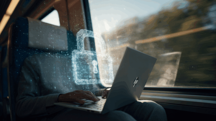 Professionnel dans un train utilisant un ordinateur portable HP avec hologramme de cadenas, illustrant la sécurité en mobilité.